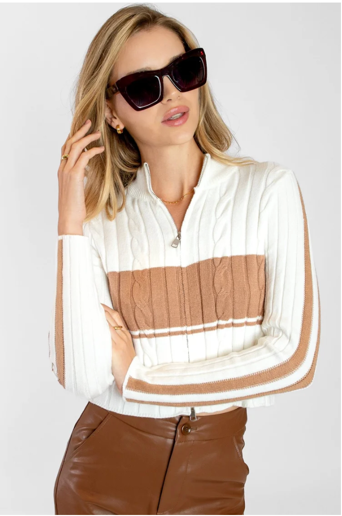 Woman wearing a striped shirt with a pocket, sunglasses, and brown pants on a white background