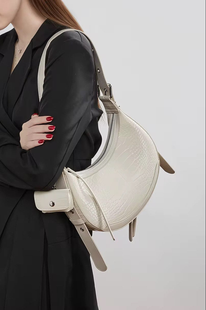 Woman holding a beige handbag against a plain background