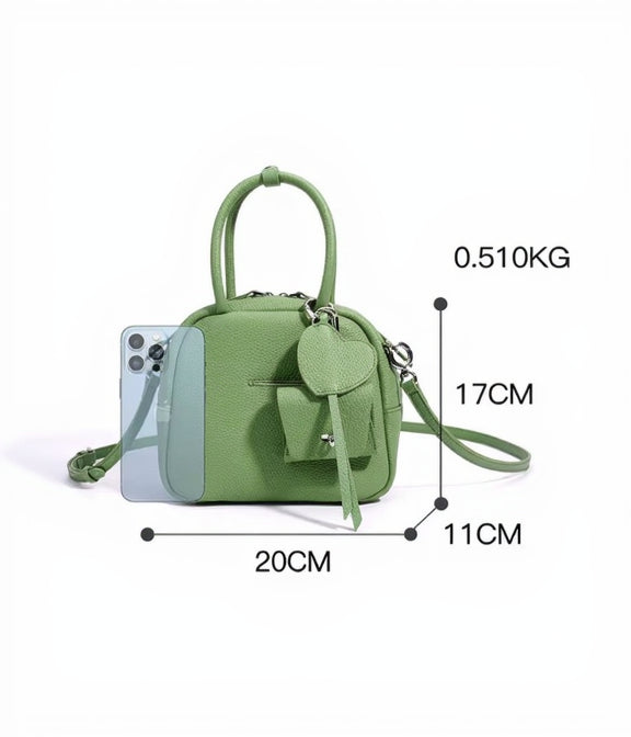 Green handbag with measurements and an iPhone for scale on a white background