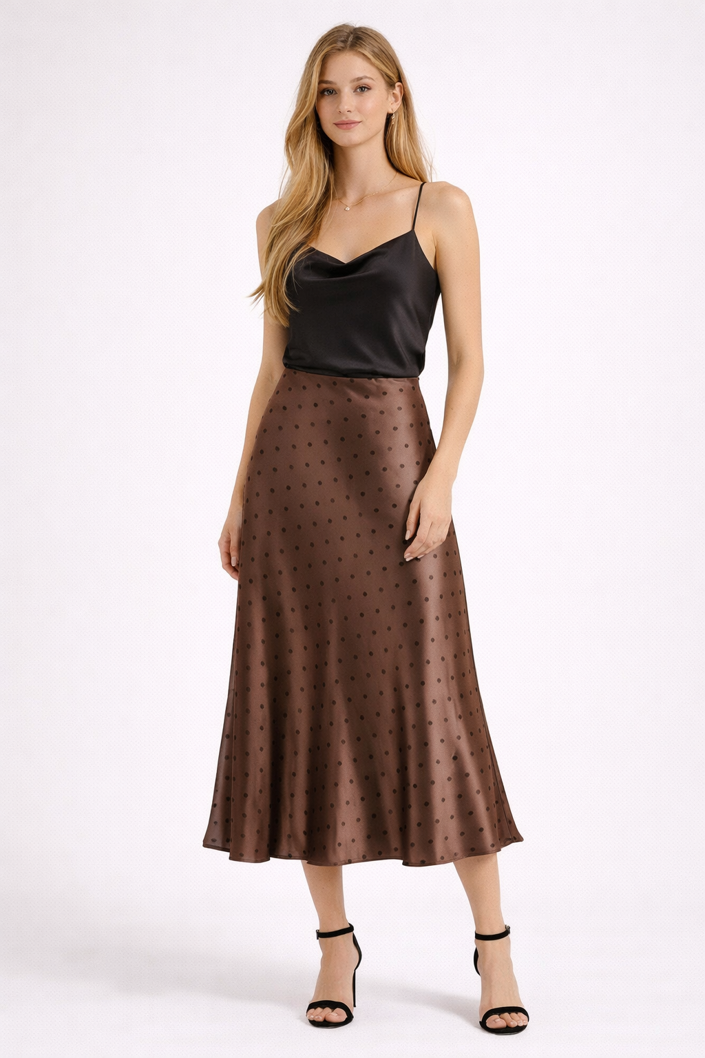 Woman wearing a black top and brown polka dot skirt on a white background