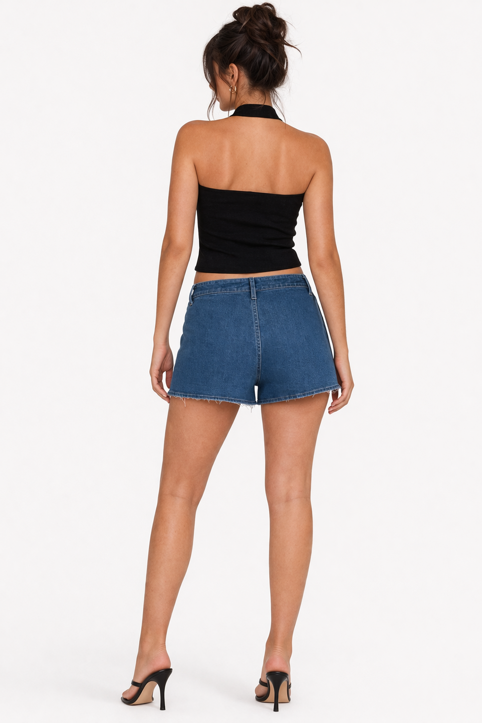 Woman wearing a black halter top and blue denim shorts on a white background
