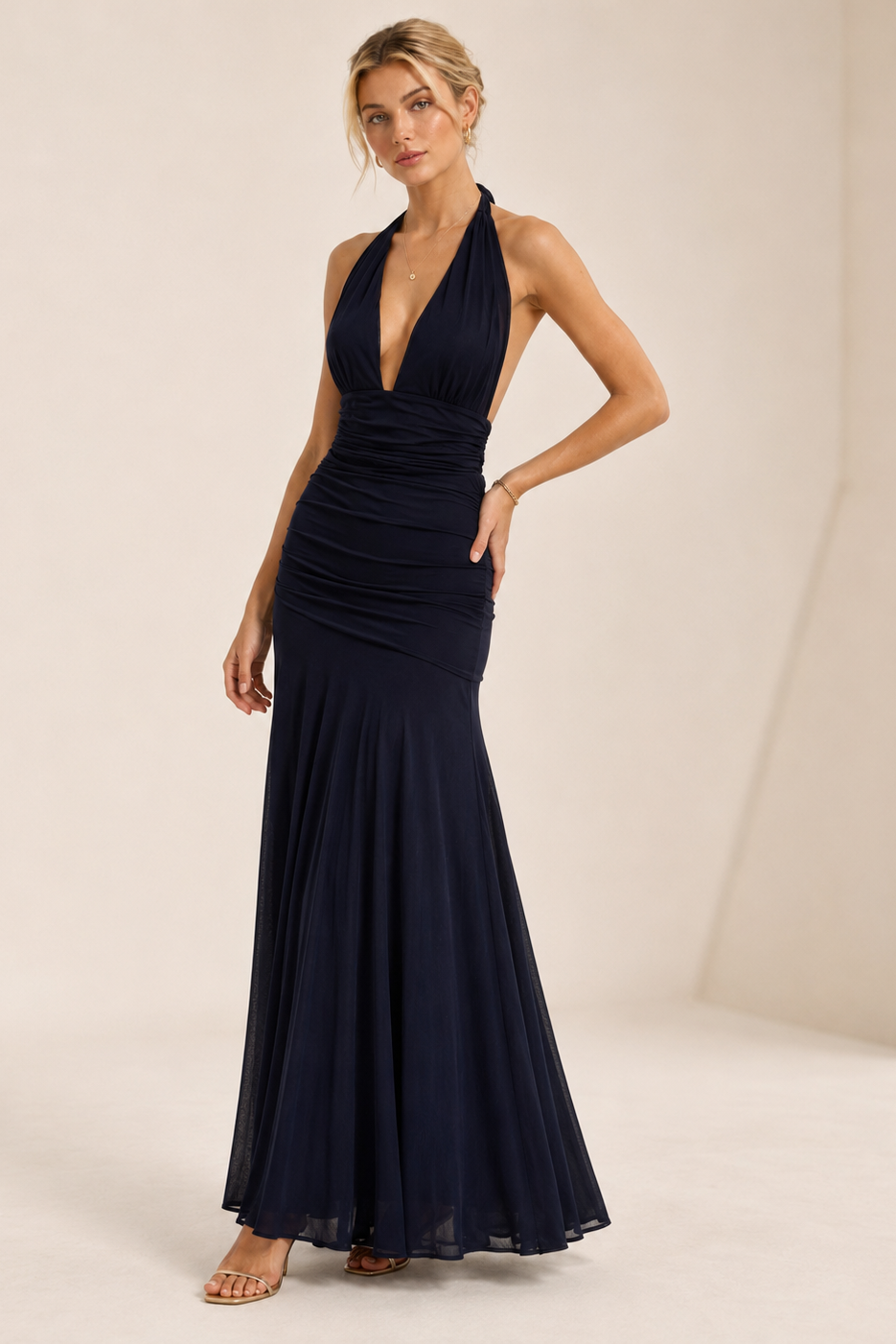 Woman wearing a navy blue evening gown against a plain background