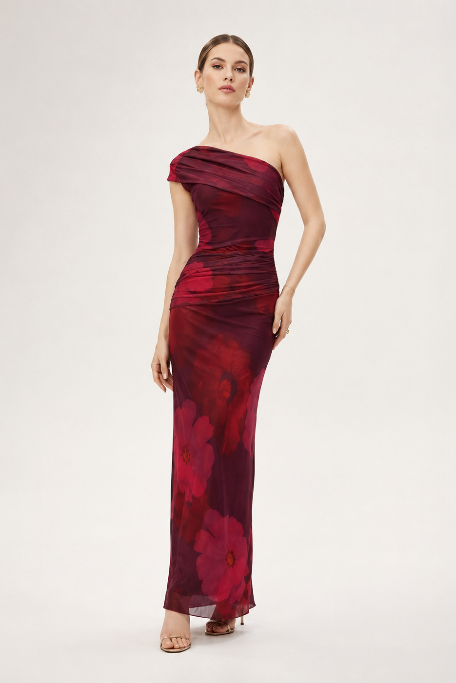 Woman wearing a burgundy one-shoulder dress with floral pattern on a white background