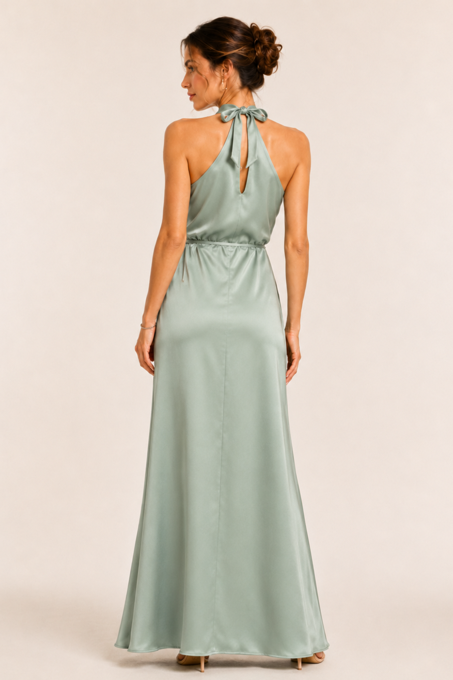 Woman wearing a light green halter neck dress on a plain background