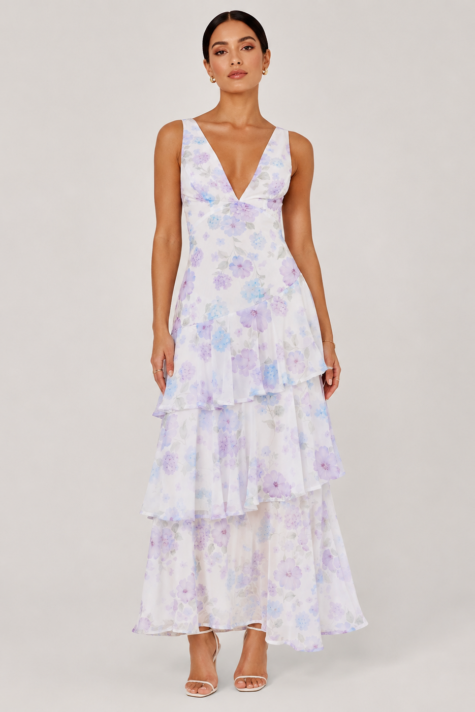 Woman wearing a floral tiered dress on a plain background