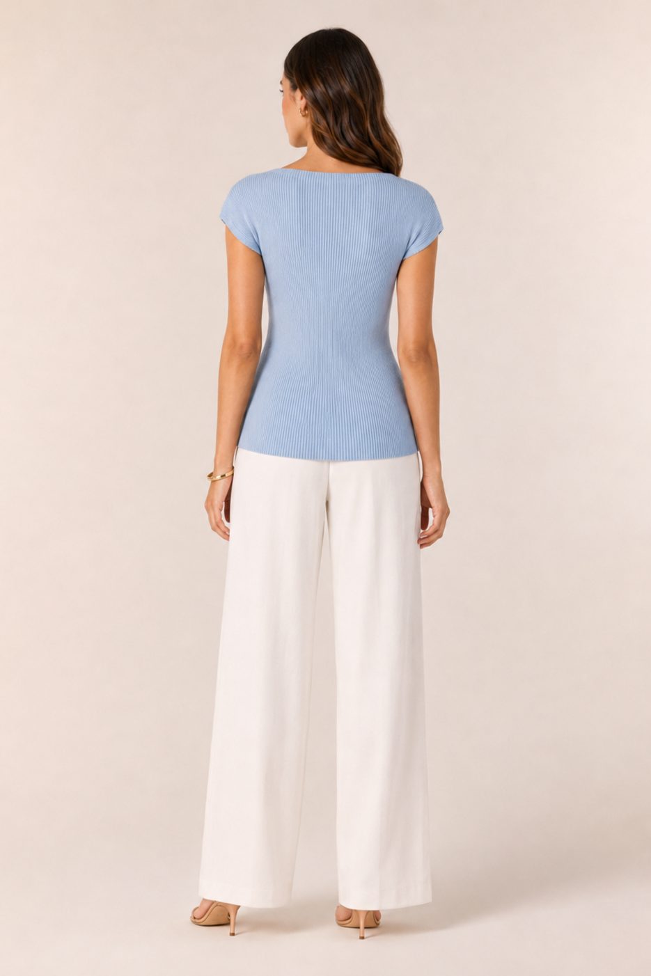 Woman wearing a light blue top and white pants on a beige background