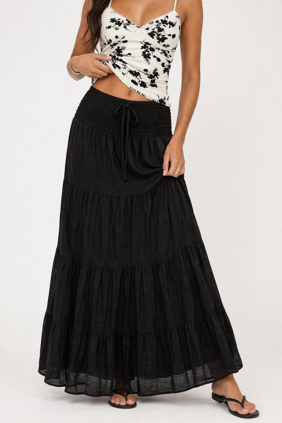 Woman wearing a black tiered skirt with a white and black patterned top on a white background