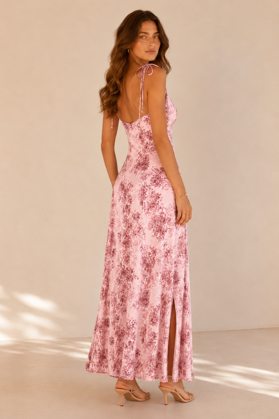 Woman wearing a pink floral dress against a beige background