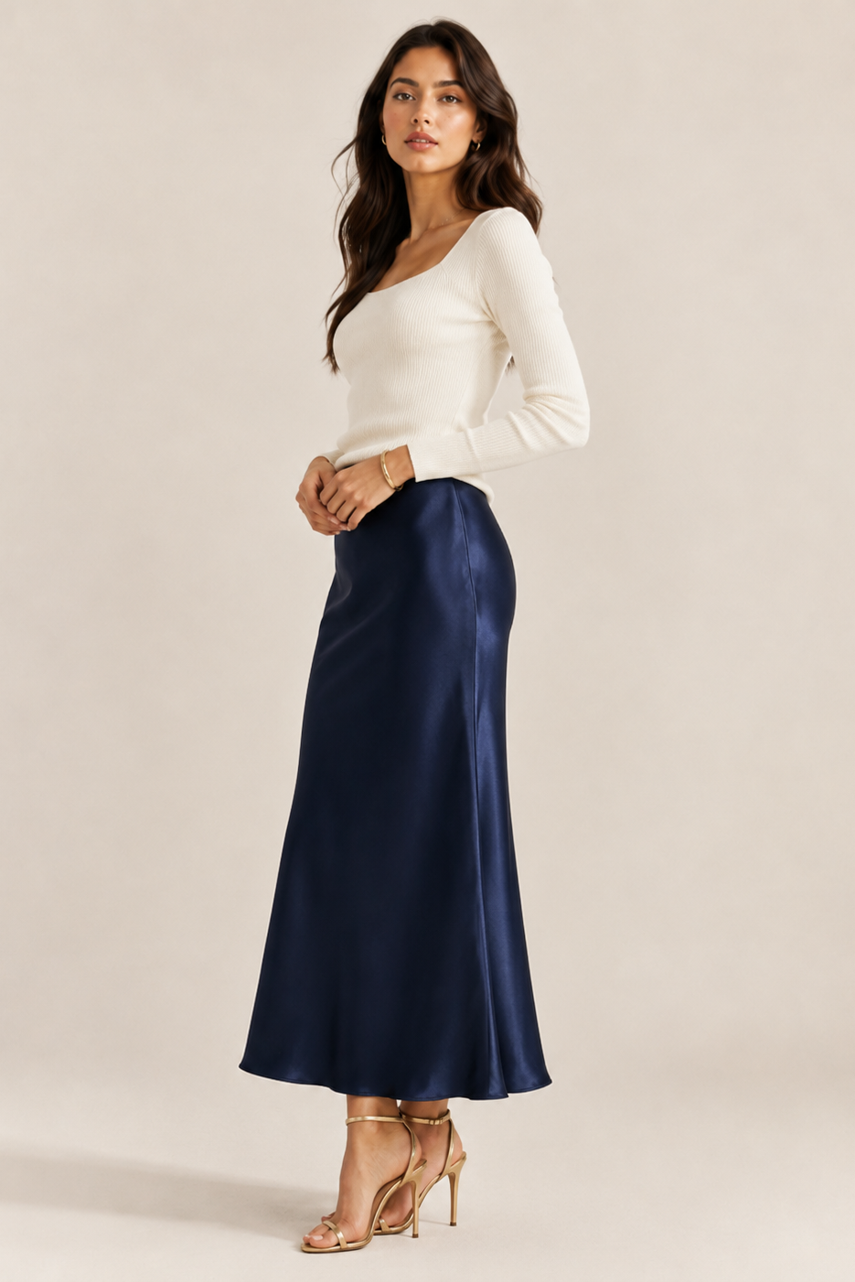 Woman wearing a white top and navy blue skirt on a plain background
