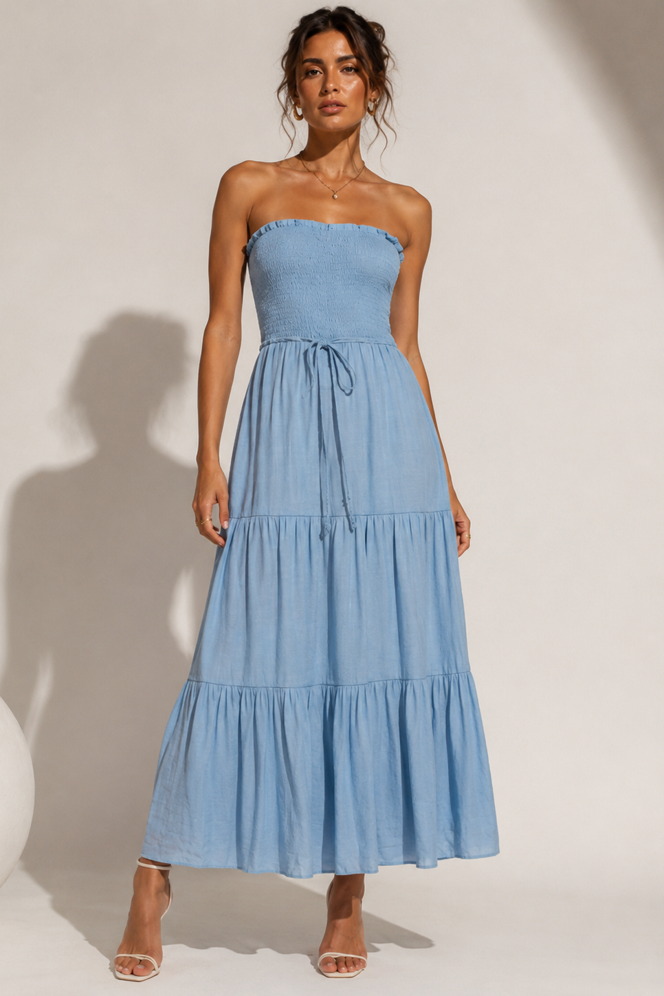 Woman wearing a blue strapless dress against a white background