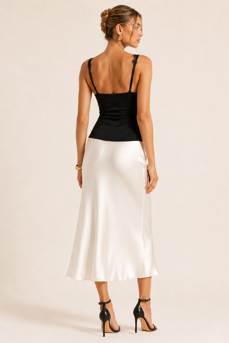 Woman wearing a black top and white satin skirt on a beige background