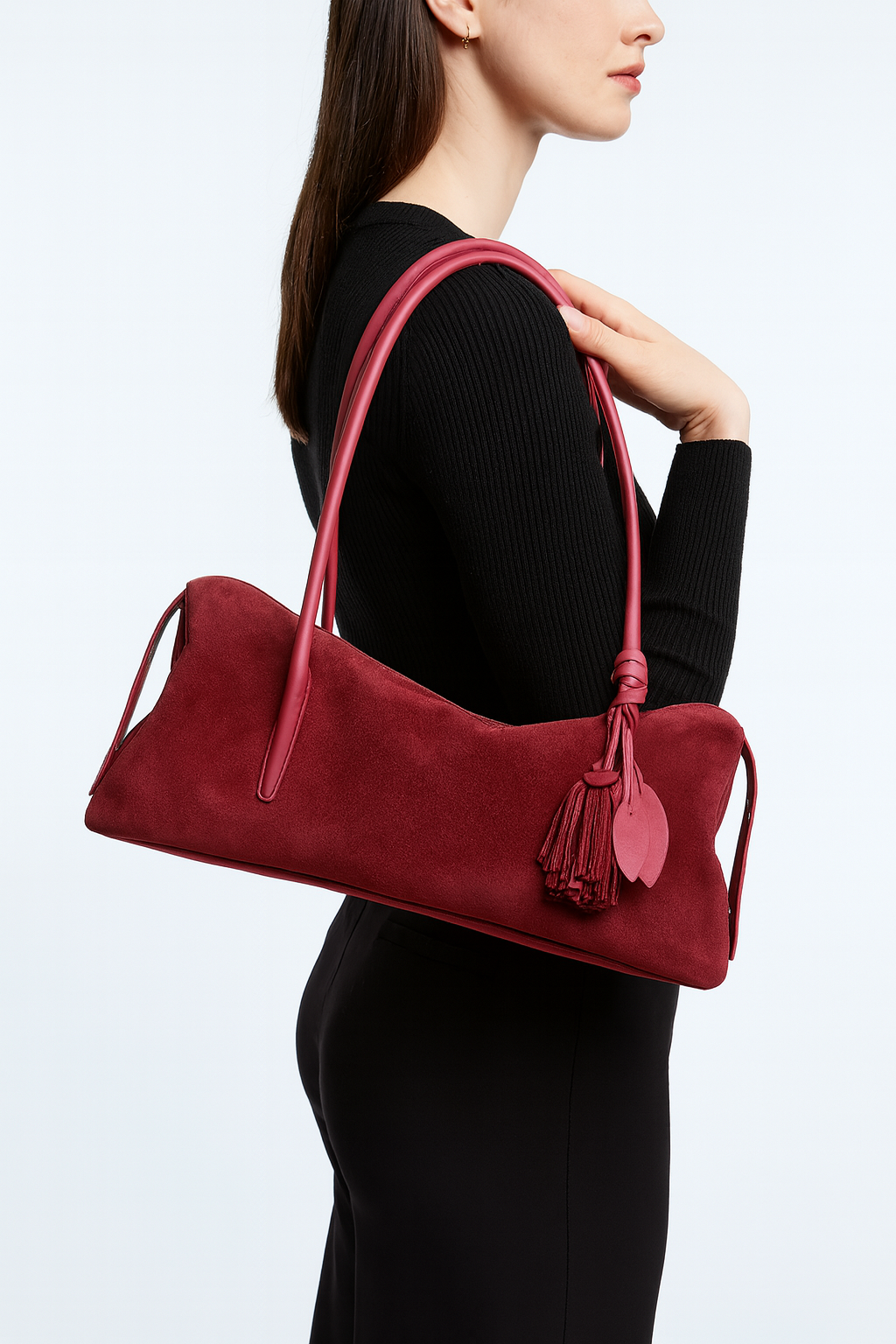 Red handbag with tassel held by a person against a white background