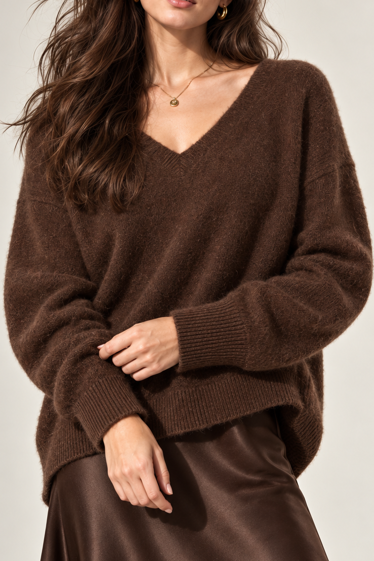A woman modeling a brown fuzzy knit V-neck sweater with long sleeves, paired with a brown satin skirt, against a light gray studio background.