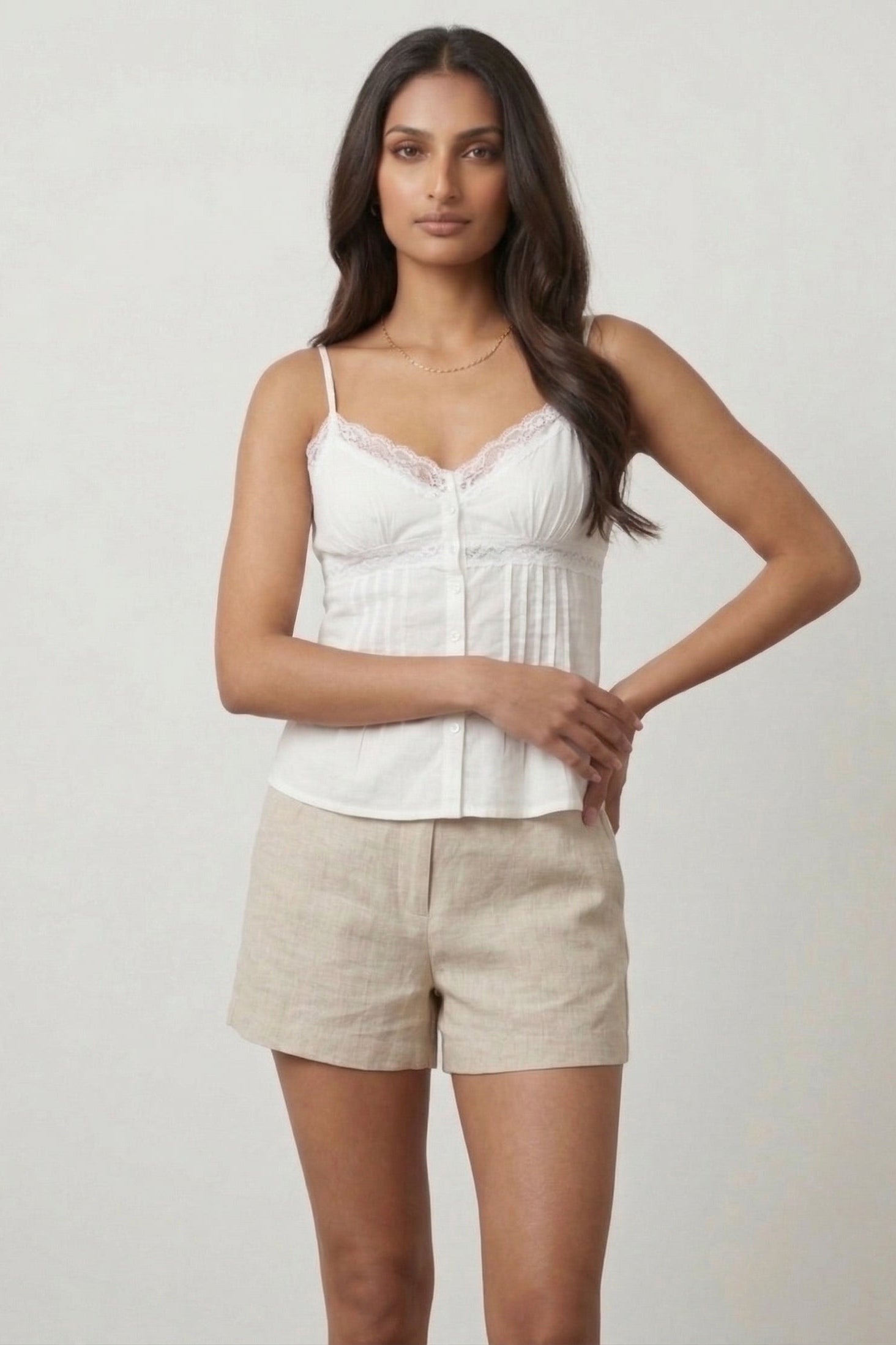 Woman wearing a white top and beige shorts against a plain background