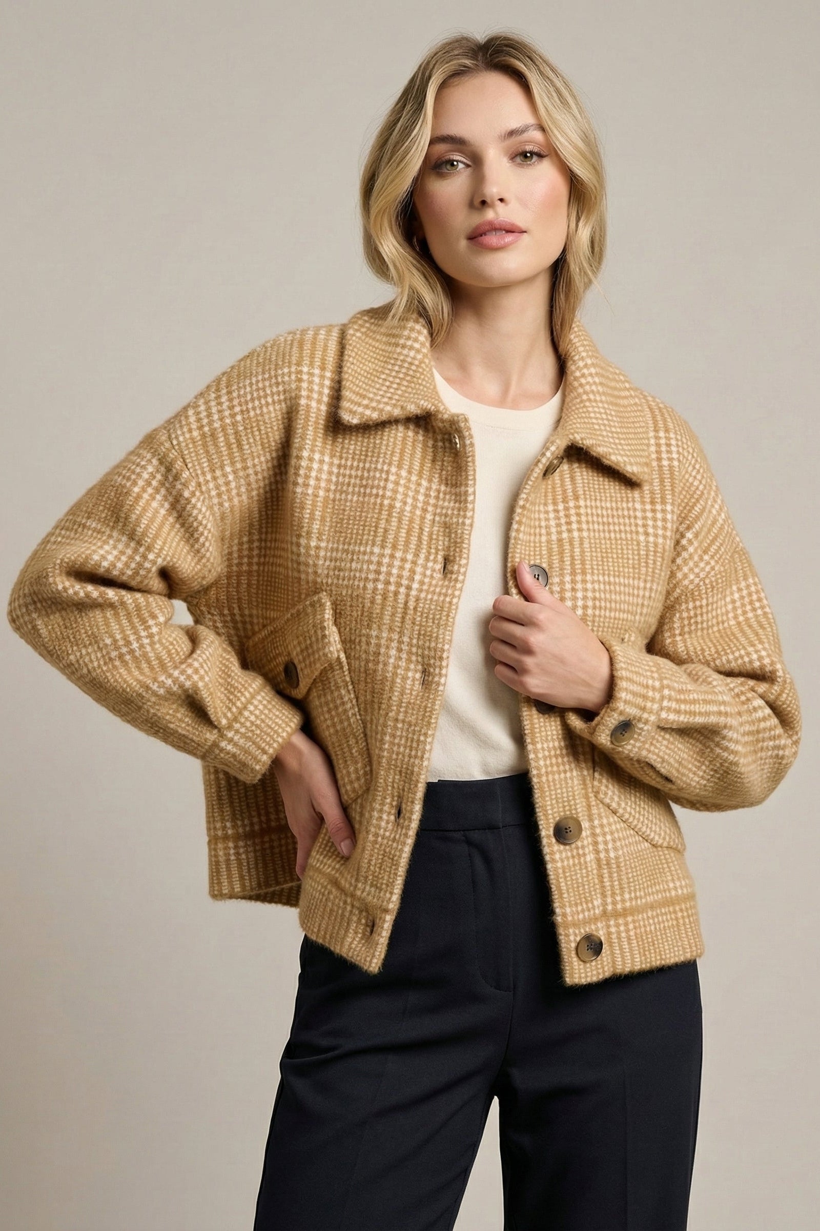 Woman wearing a beige plaid jacket on a plain background