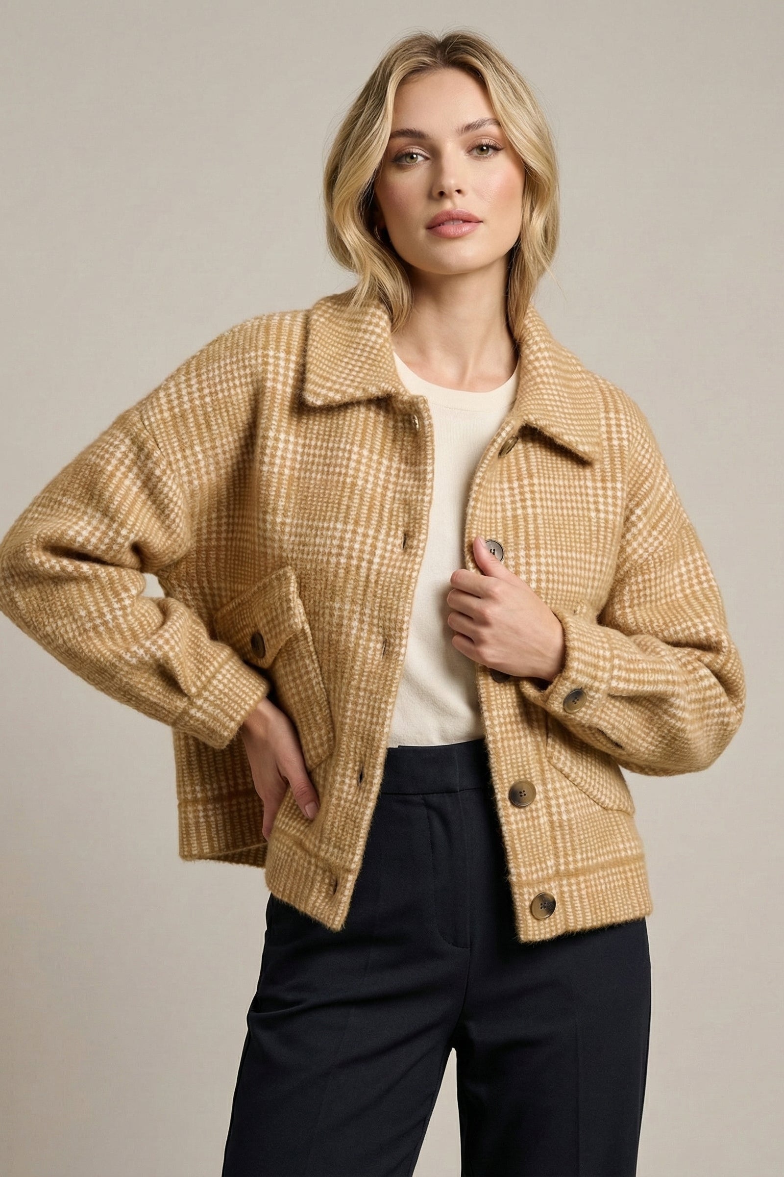 Woman wearing a beige plaid jacket on a plain background