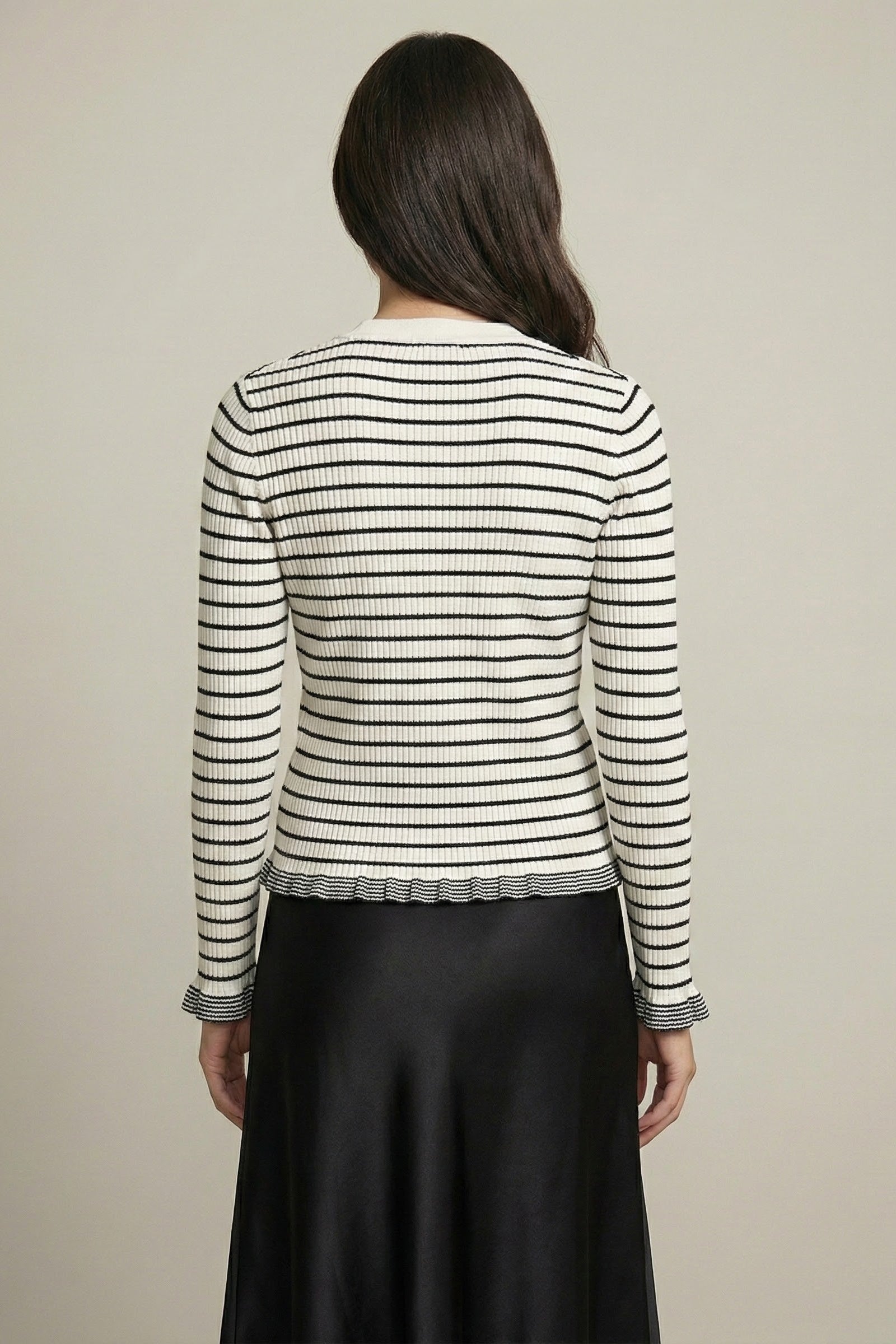 Woman wearing a black and white striped sweater with a plain background
