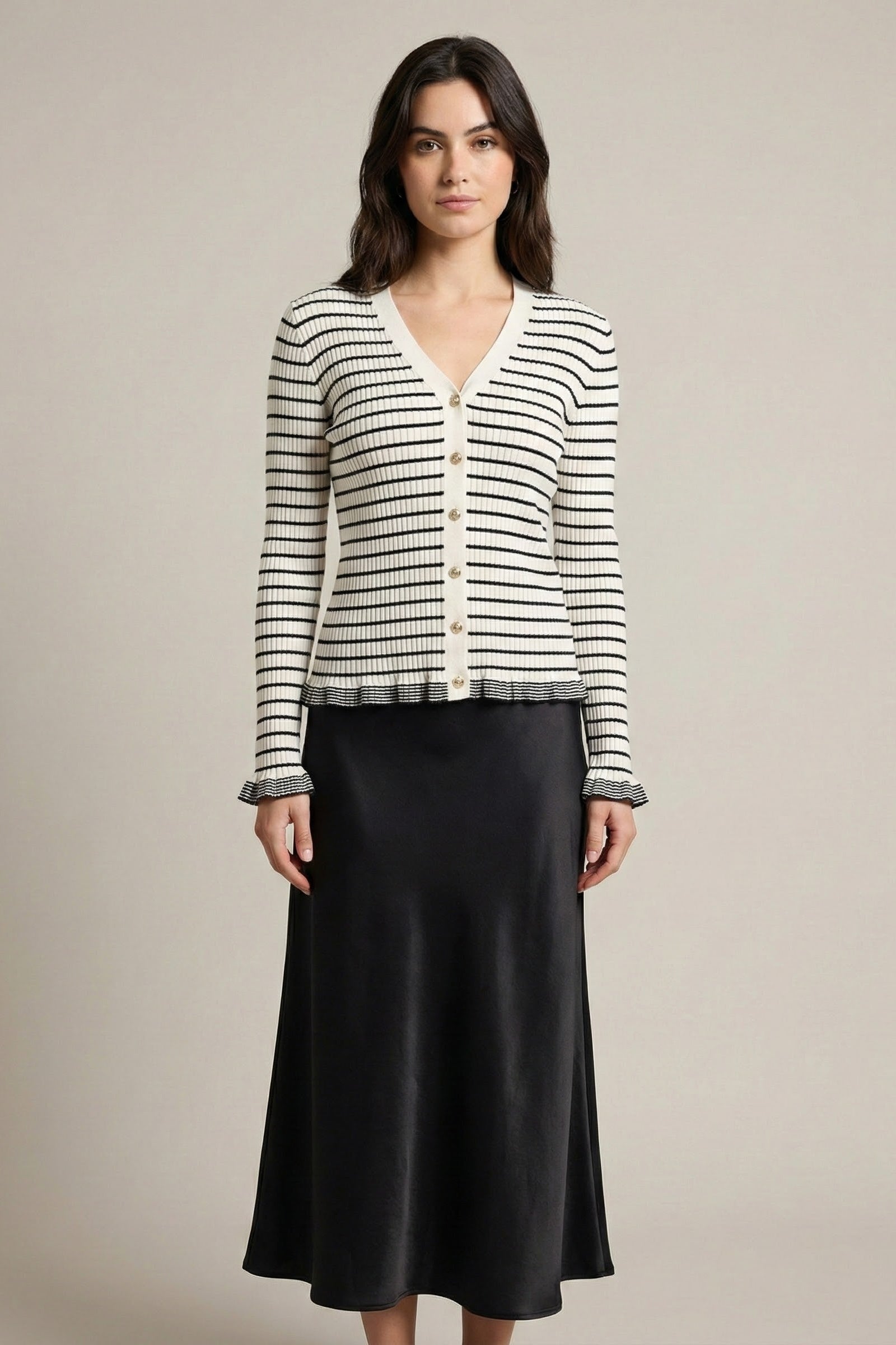 Woman wearing a striped cardigan and black skirt on a beige background