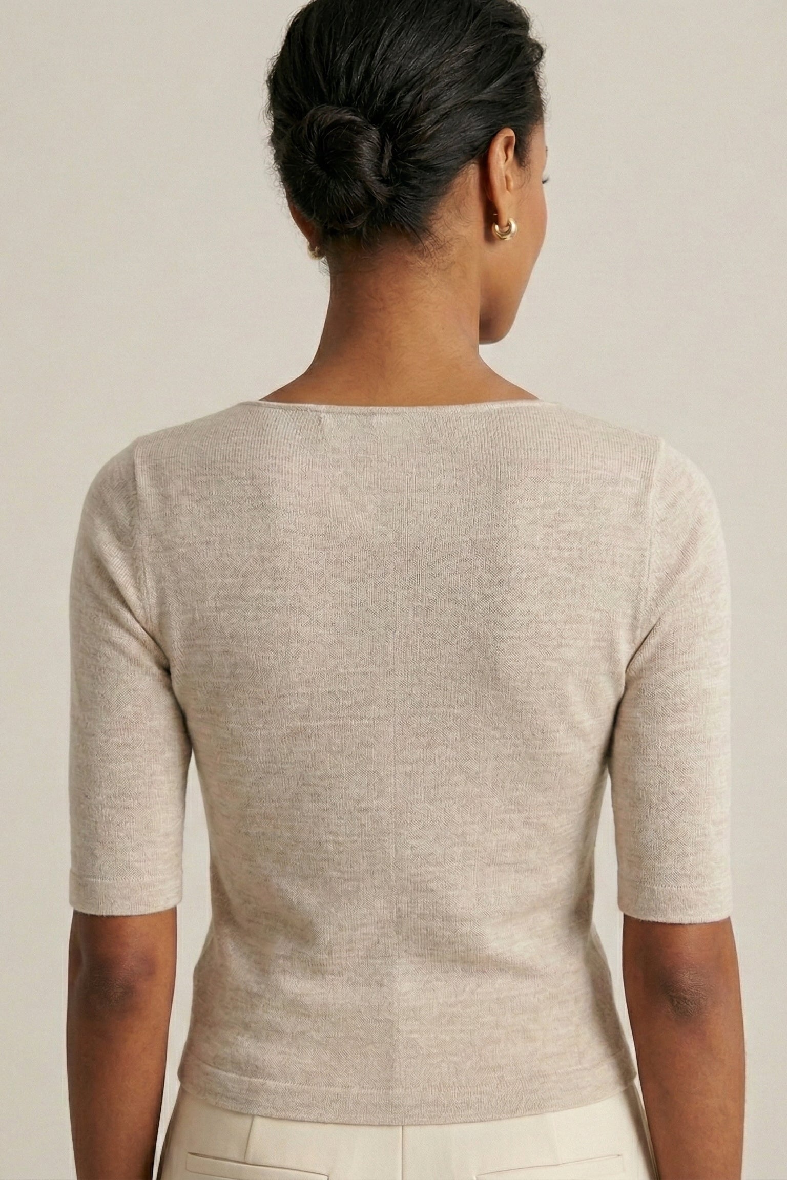 Woman wearing a beige knit cardigan against a plain background