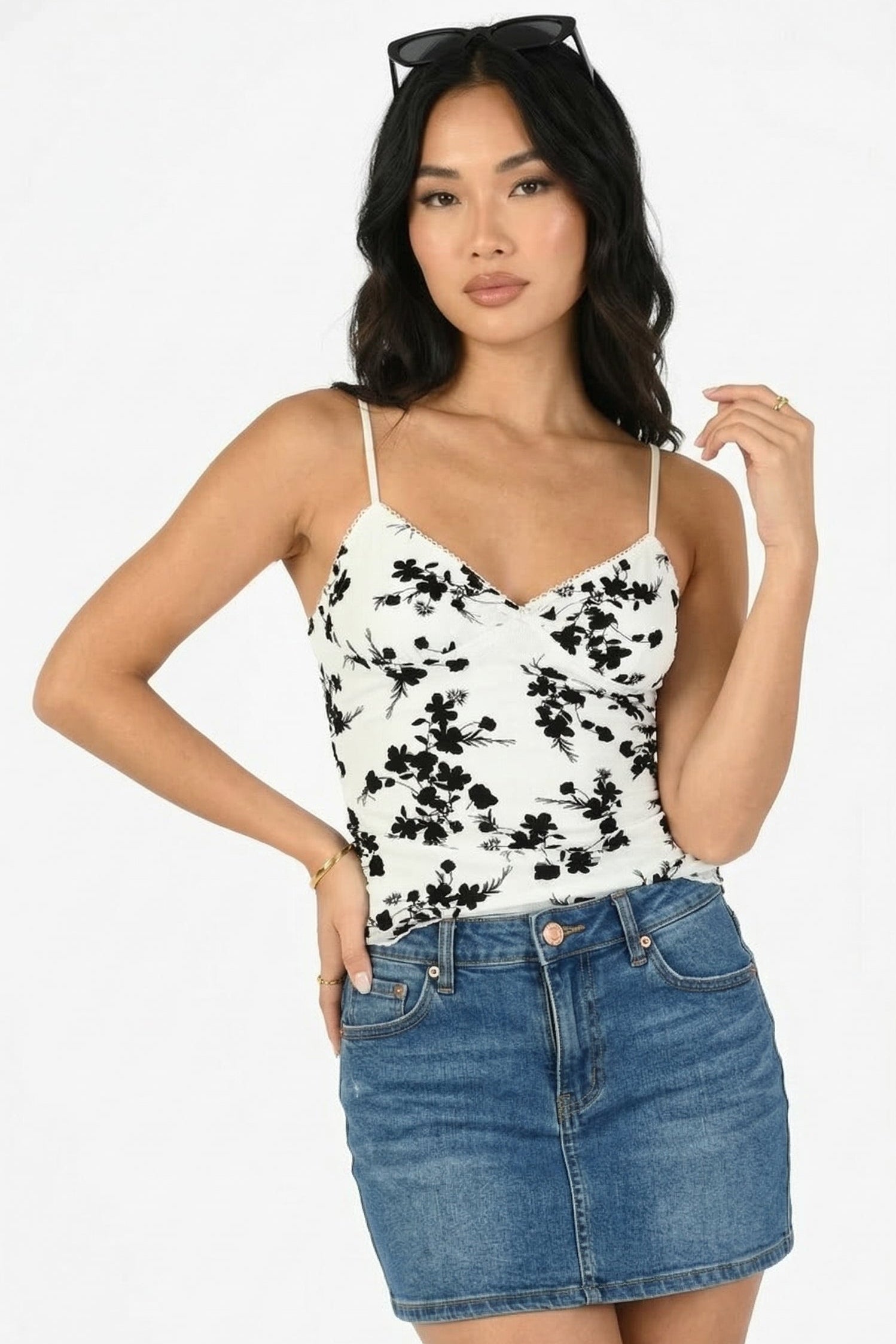 Woman wearing a floral top and denim skirt on a white background