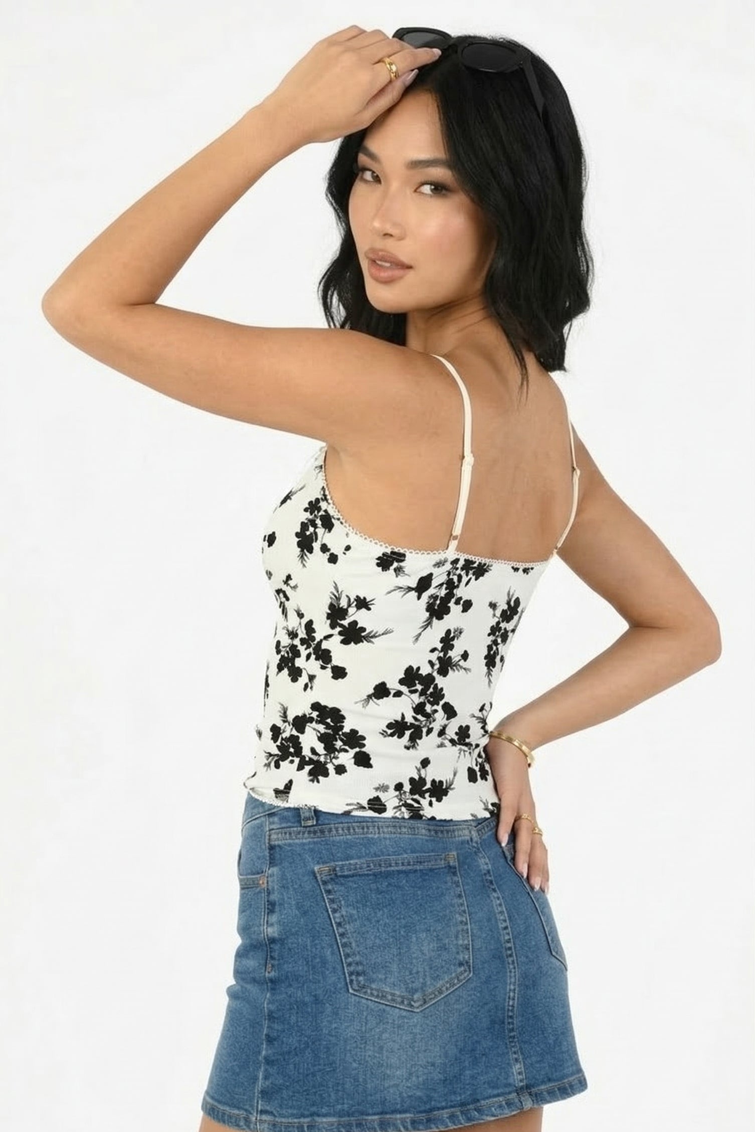 Woman wearing a floral top and denim skirt on a white background