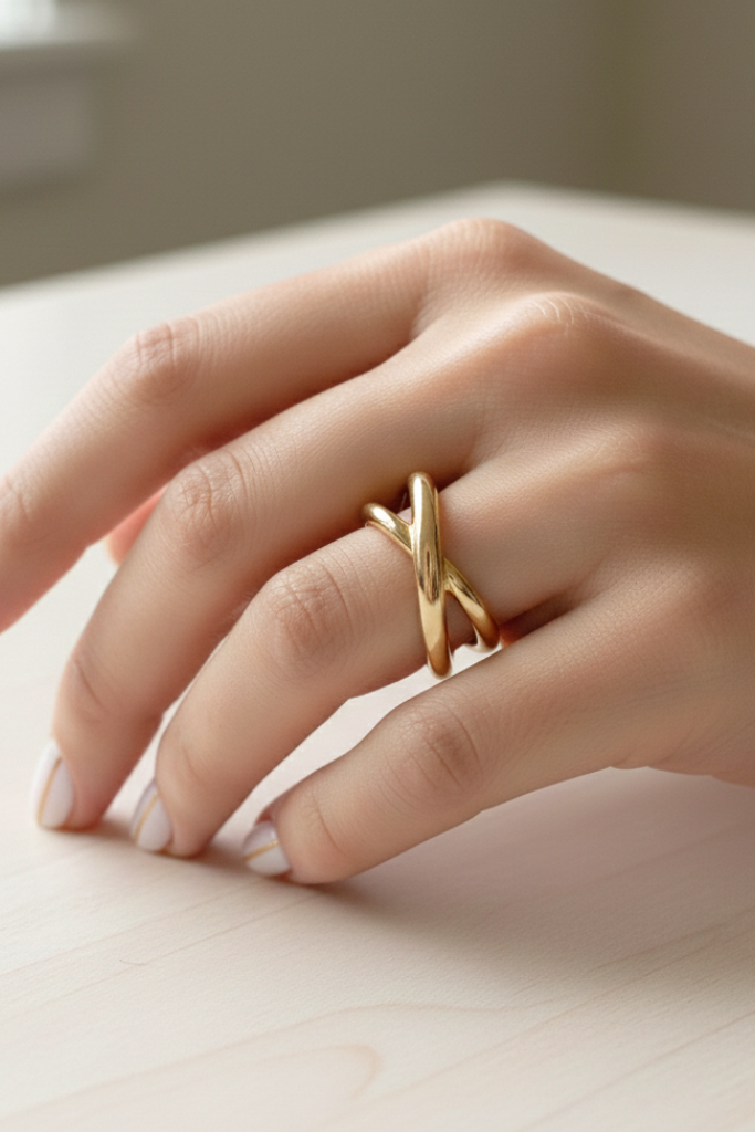 Hand wearing a gold ring on a light surface