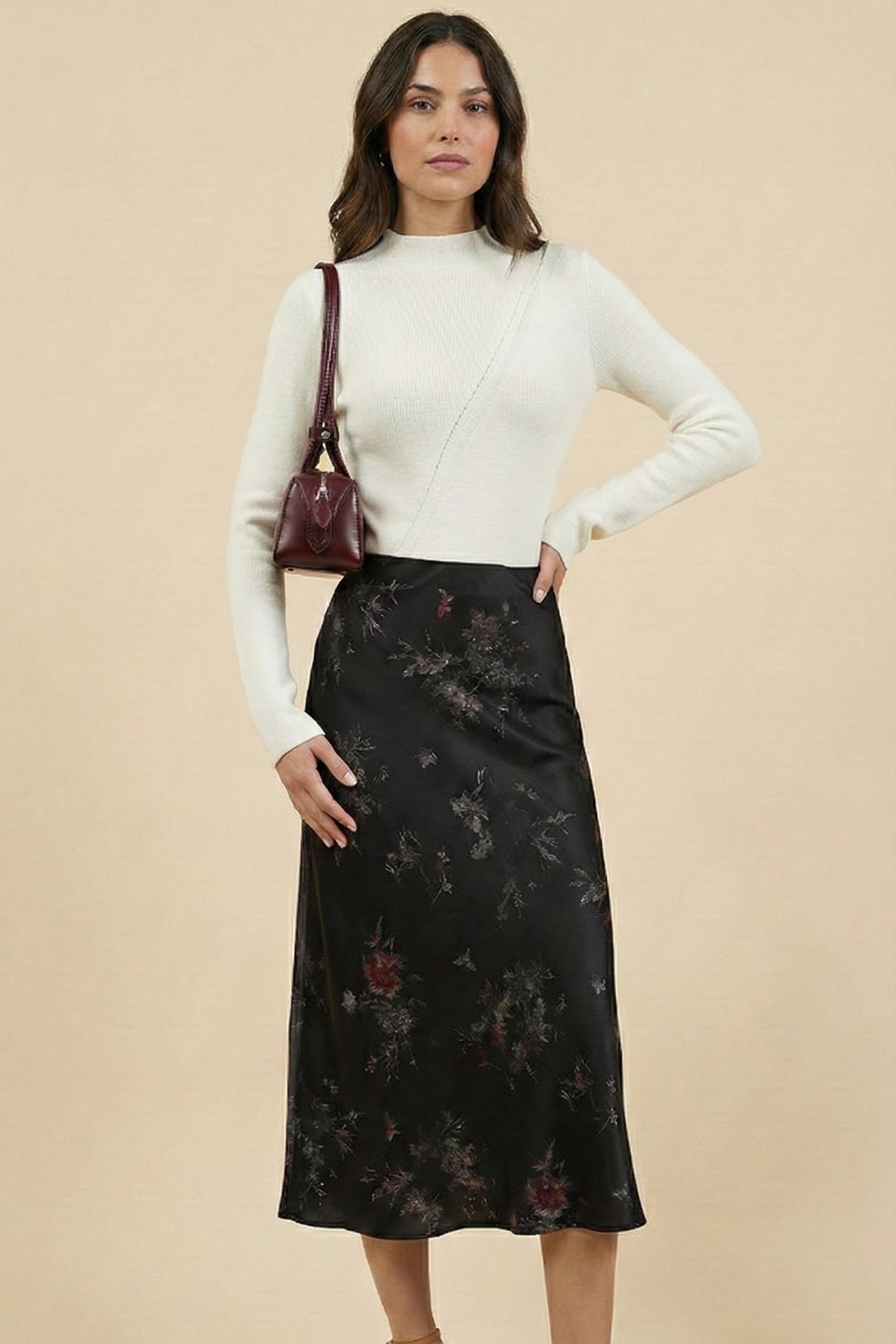 Woman wearing a black floral skirt and white top against a beige background
