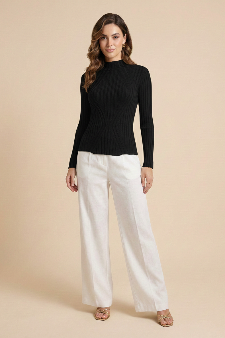 Woman wearing a black long-sleeve top and white pants on a beige background
