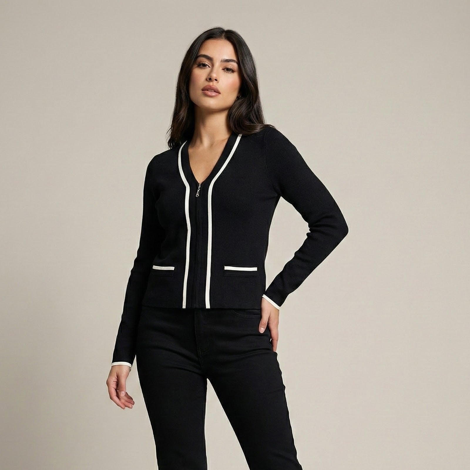 Woman wearing a black outfit with white accents on a neutral background