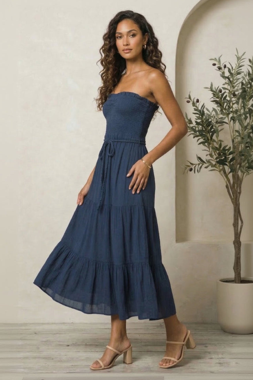 Woman wearing a blue strapless dress standing indoors with a neutral background