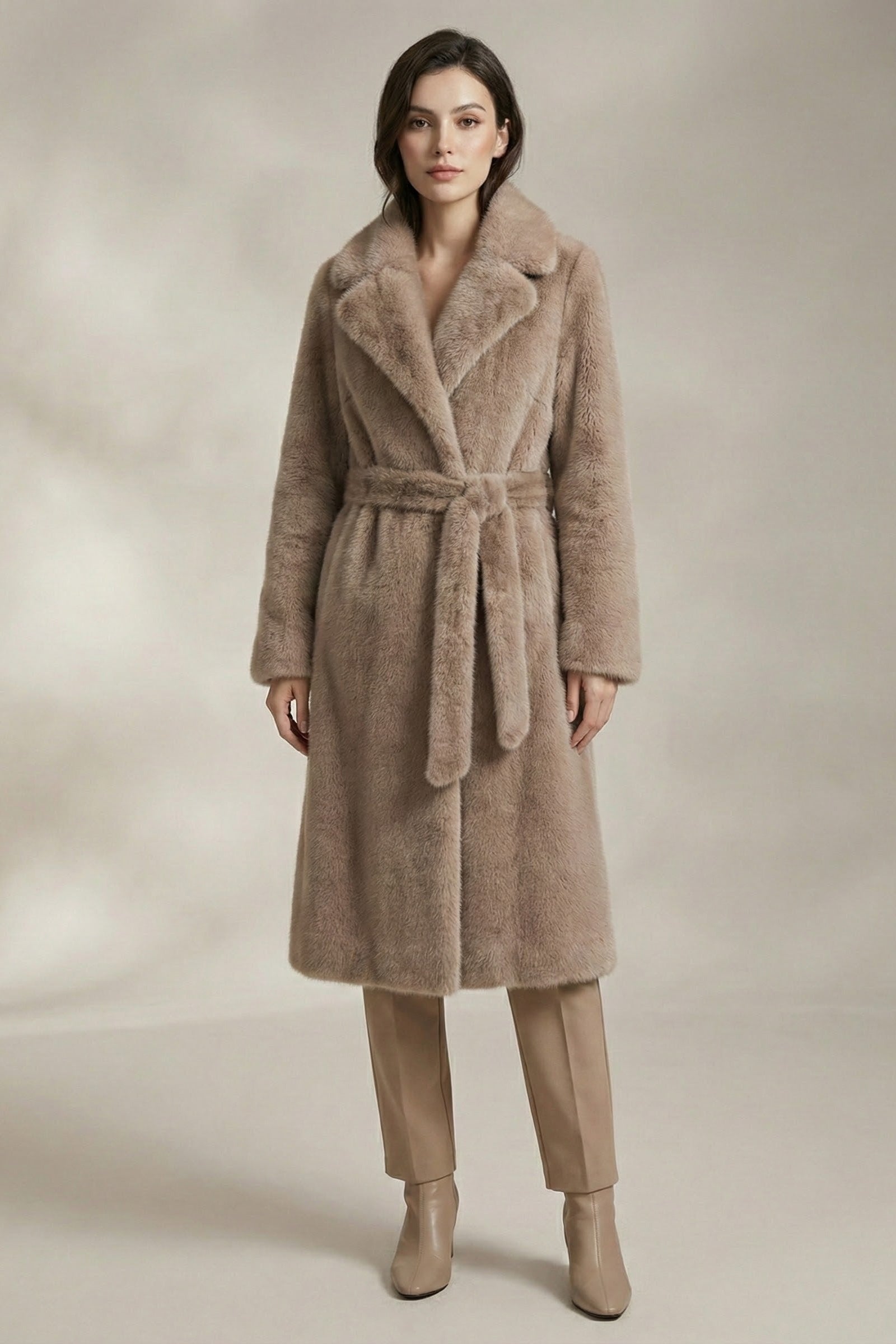 Woman wearing a beige coat with a belt on a neutral background