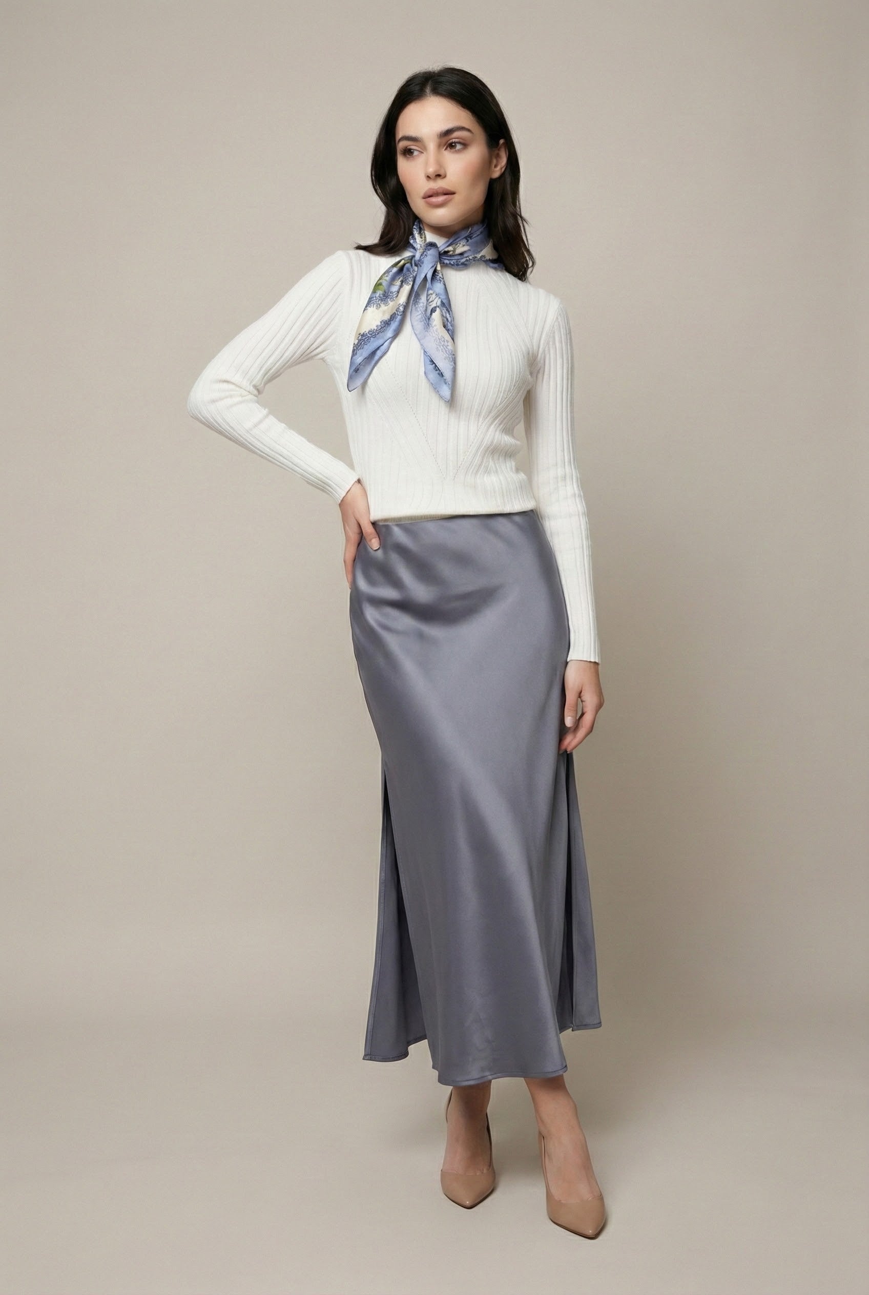 Woman wearing a white sweater and gray skirt with a blue scarf on a beige background