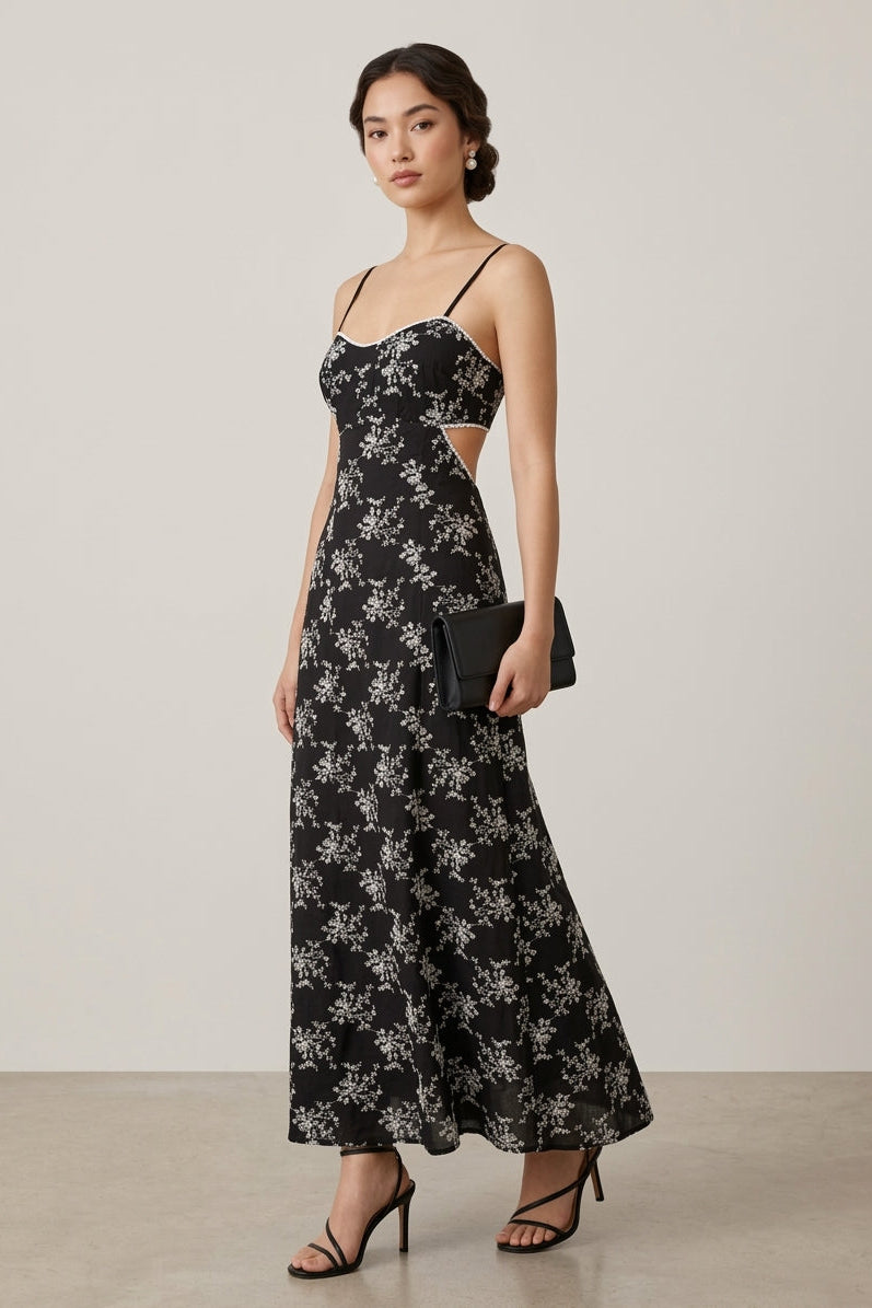 Woman wearing a black floral dress with cut-out details on a plain background