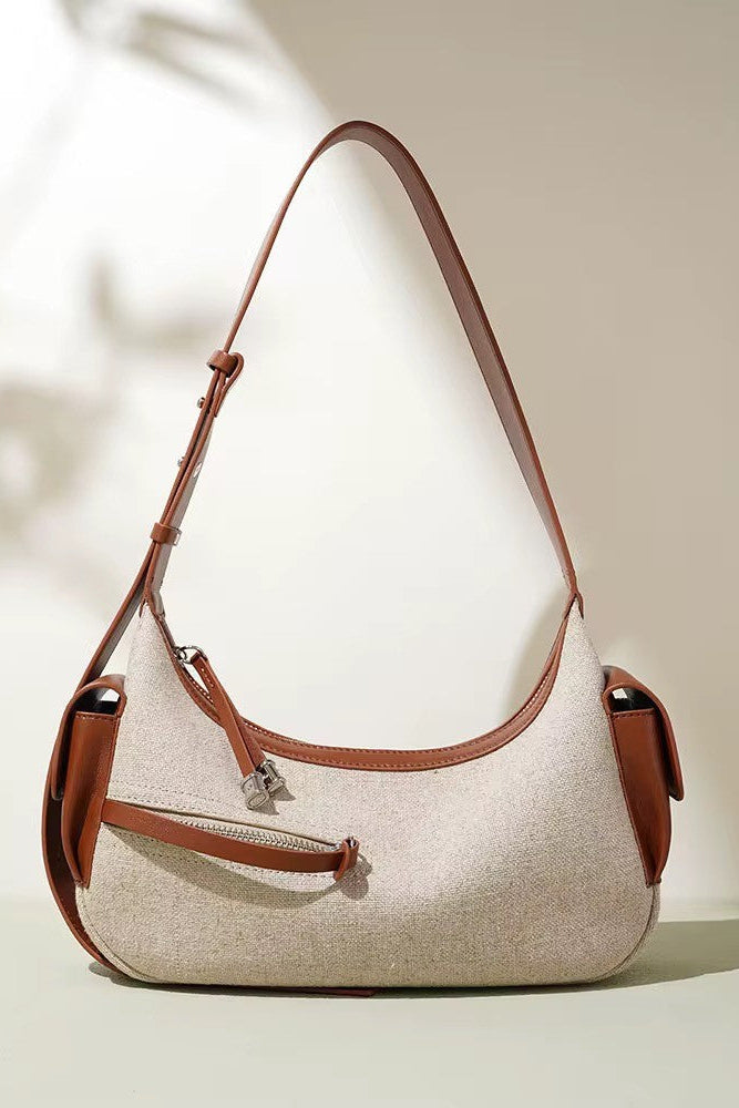 Beige handbag with brown leather accents on a light background