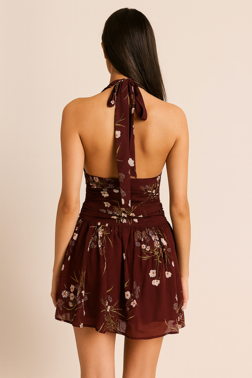 Woman wearing a burgundy floral dress with a beige background