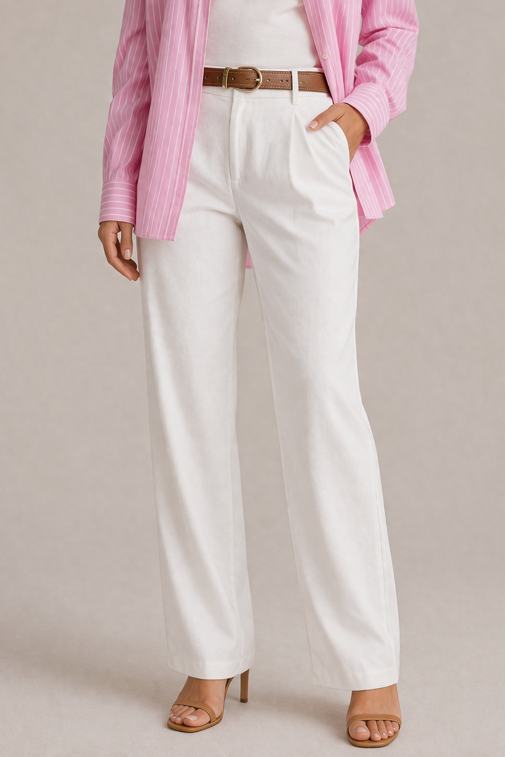 Person wearing white pants with a pink shirt and brown belt on a neutral background