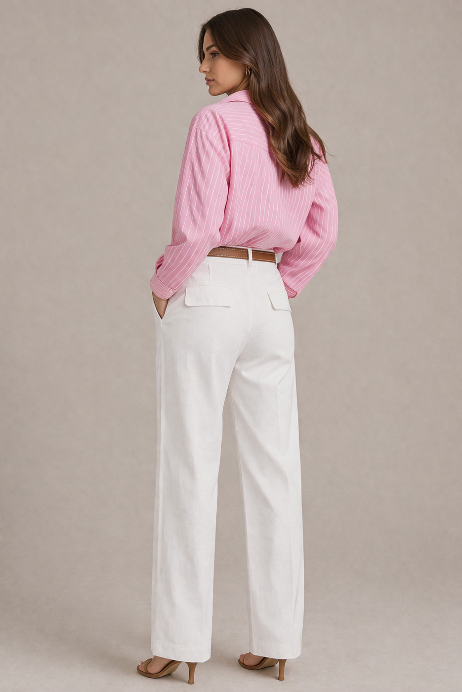 Woman wearing a pink blouse and white pants against a beige background