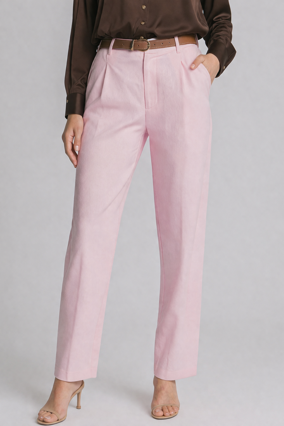 Person wearing pink pants and a brown shirt on a gray background