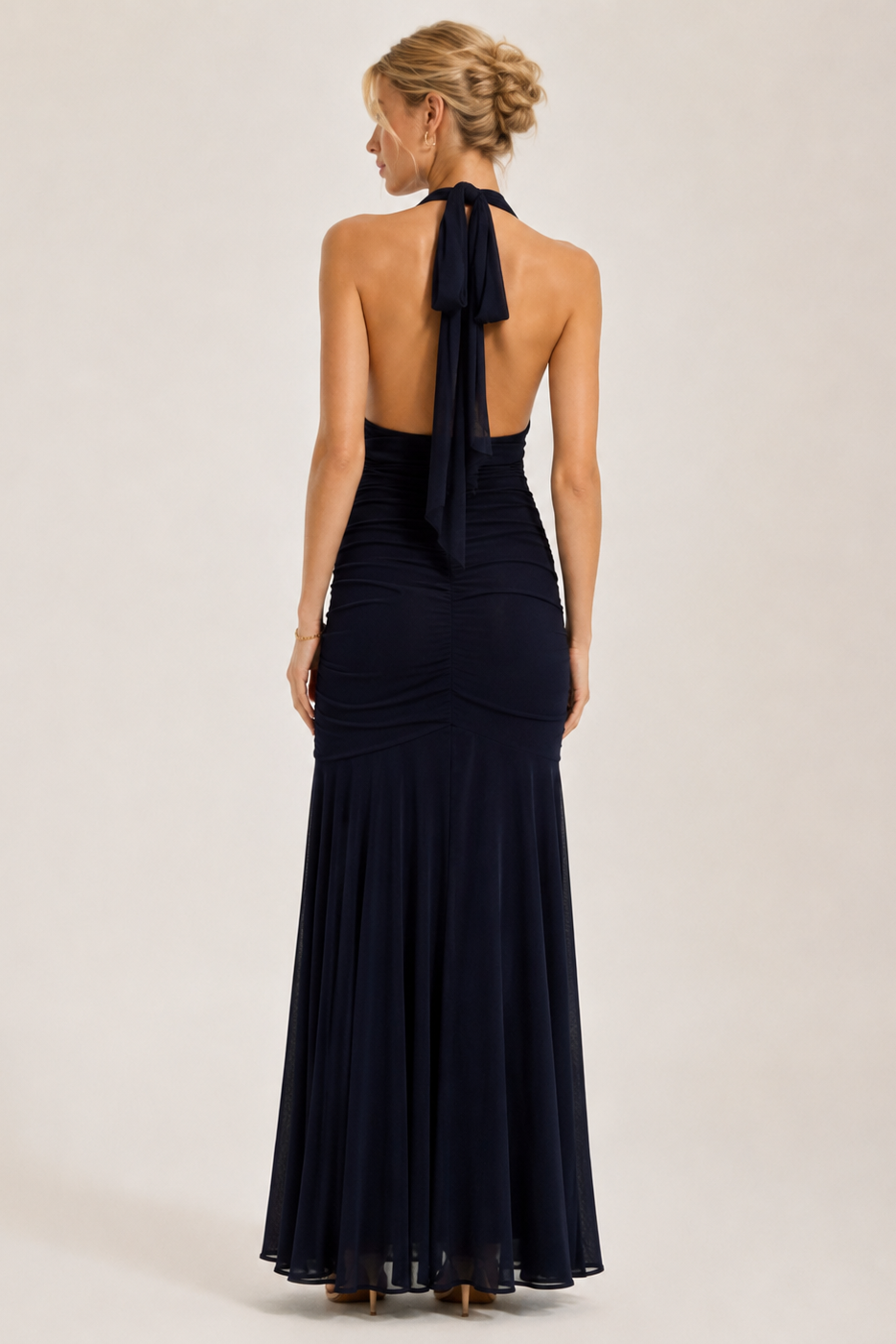 Woman wearing a black halter neck gown on a plain background