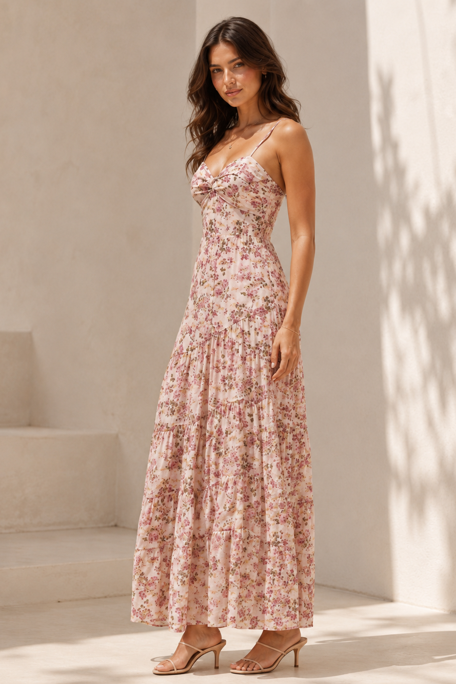 Woman wearing a floral dress standing in a sunlit room with white walls and steps.