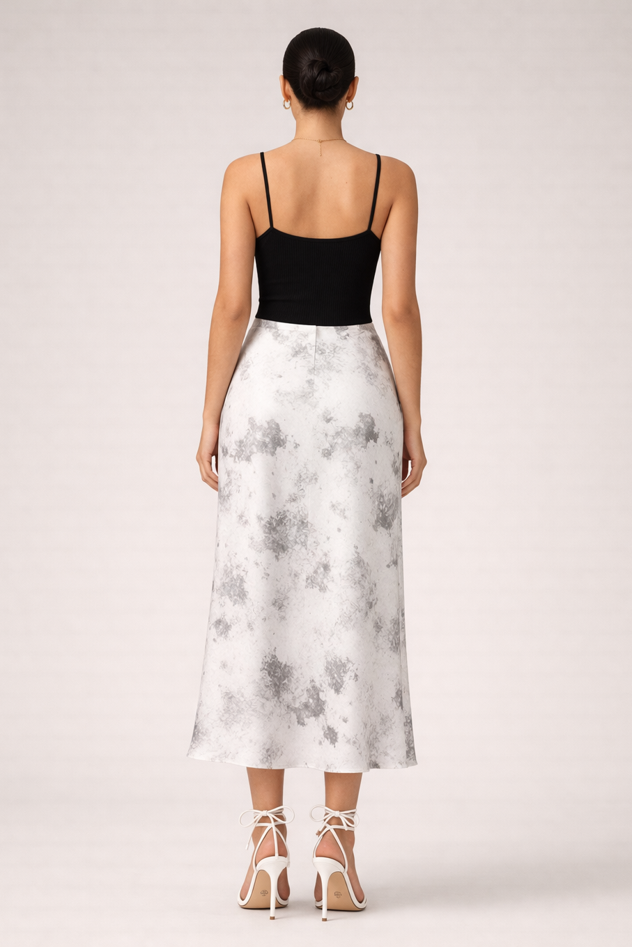 Woman wearing a black top and white floral skirt on a white background