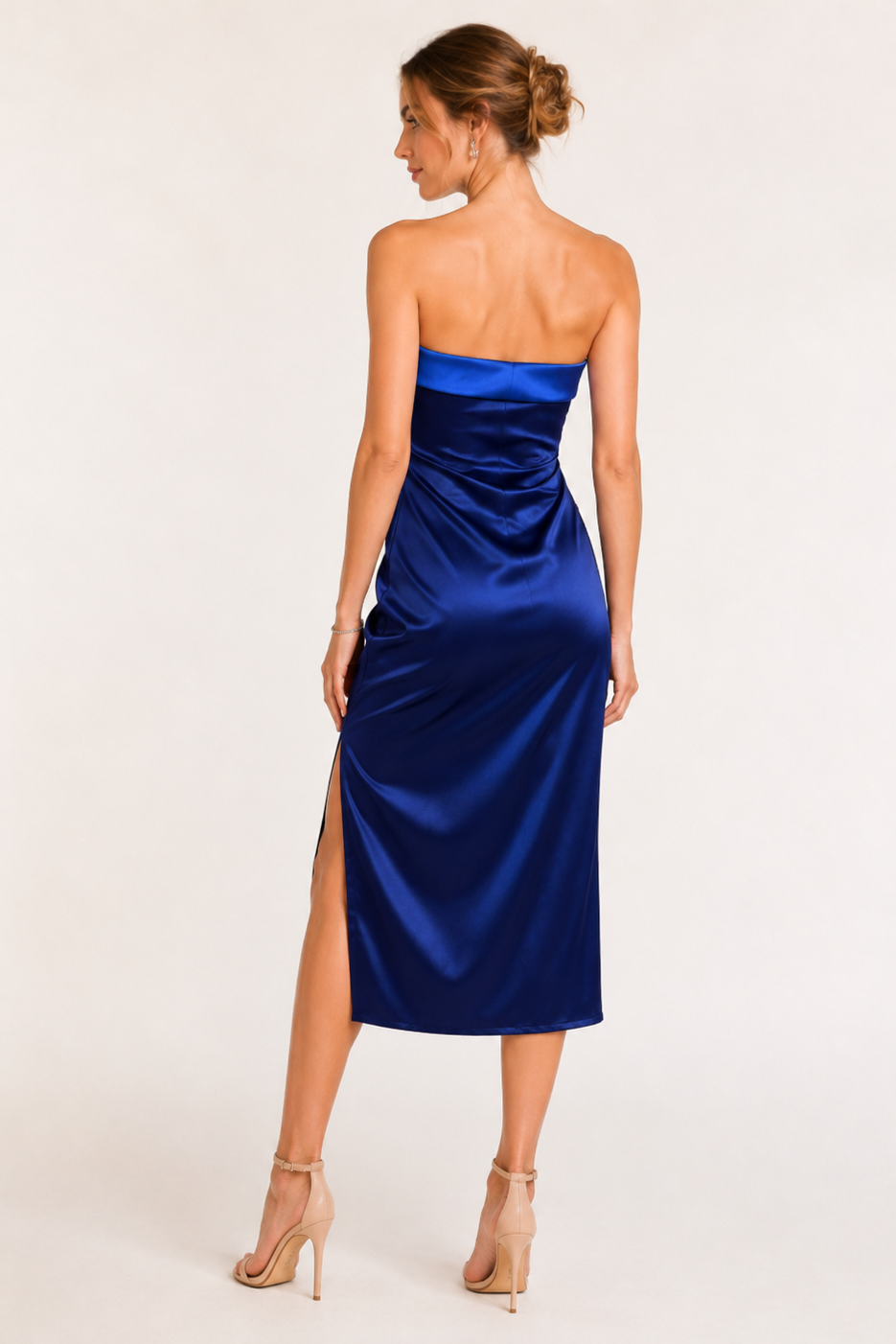 Woman wearing a blue strapless dress with a slit on a white background