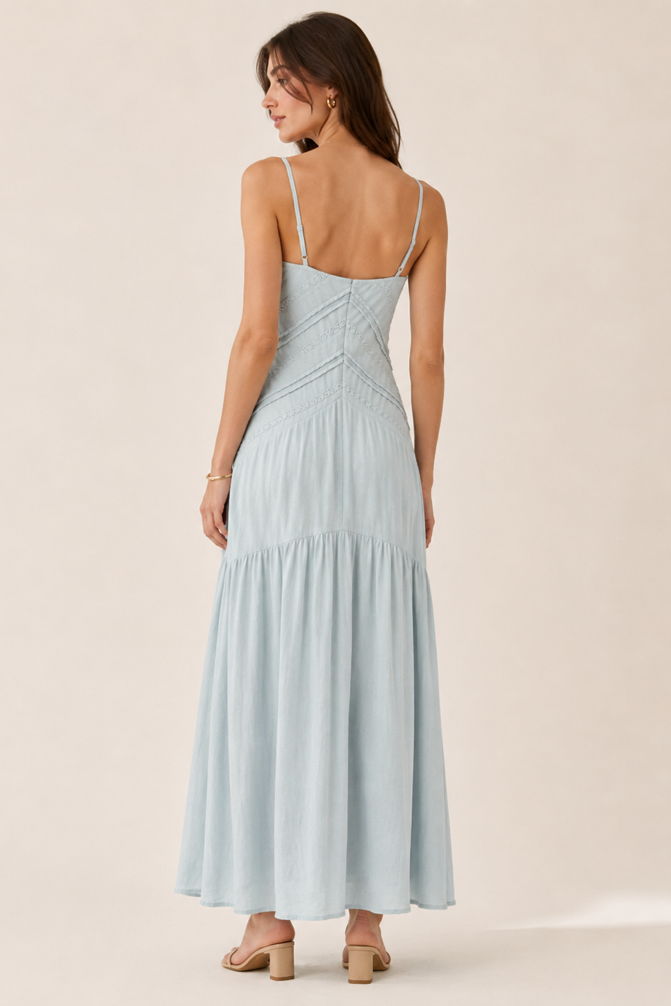 Woman wearing a light blue dress with thin straps on a beige background