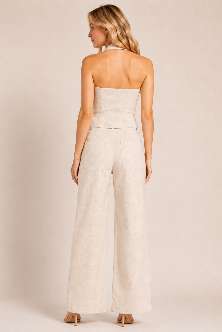 Woman wearing a strapless jumpsuit on a plain background