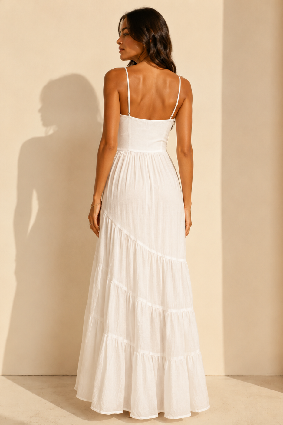 Woman wearing a white dress against a beige wall