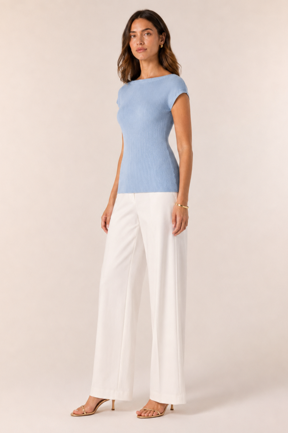 Woman wearing a light blue top and white pants on a beige background