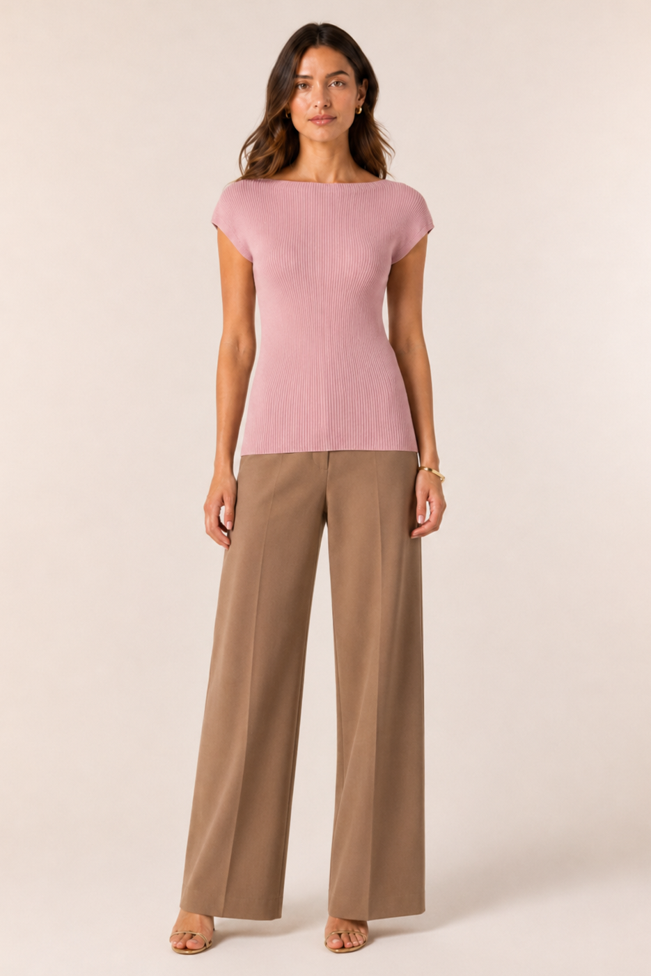 Woman wearing a pink top and beige pants on a white background