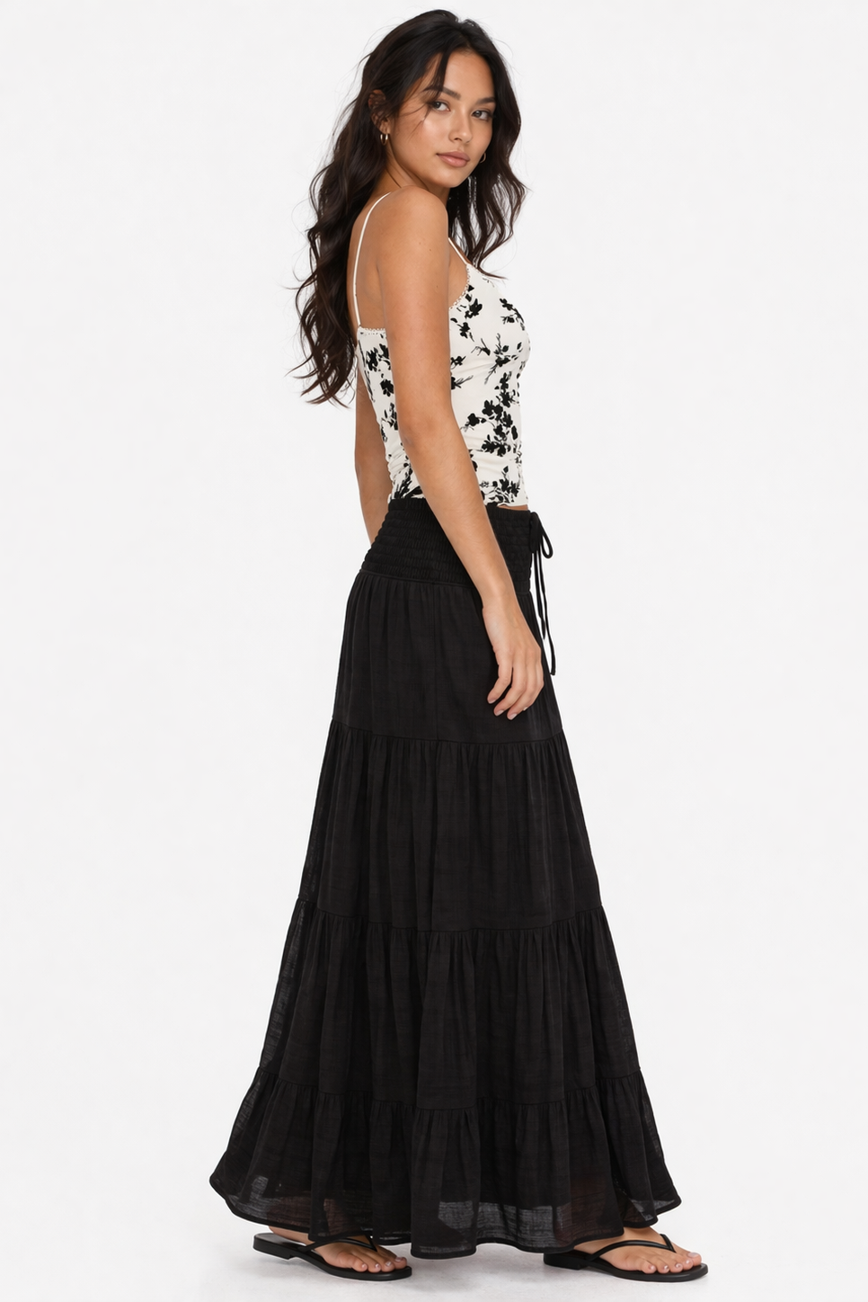 Woman wearing a black and white floral top with a long black skirt on a white background