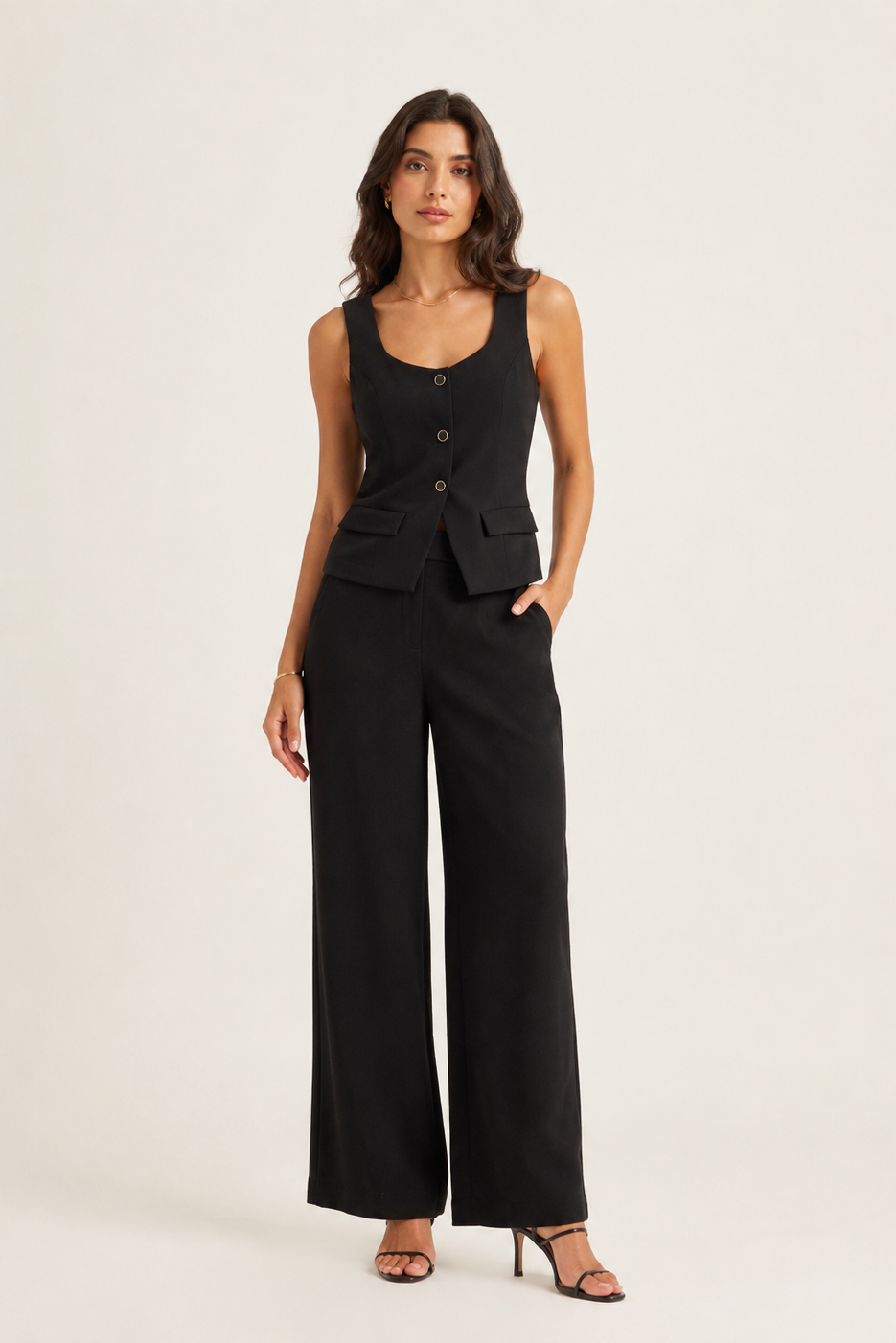 Woman wearing a black sleeveless top and wide-leg pants on a white background