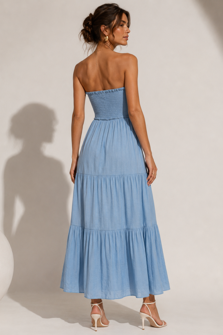 Woman wearing a blue strapless dress against a white background